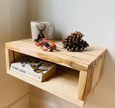 a wooden table topped with a coffee cup next to a pine cone on top of it