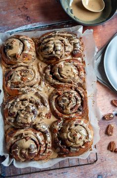 cinnamon rolls with icing and pecans on a wooden table