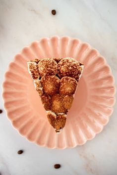 a pink plate topped with a slice of cake covered in powdered sugar next to coffee beans