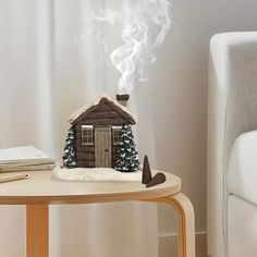 a small wooden house sitting on top of a table next to a white chair and book