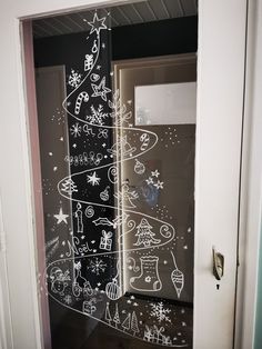 an open door with chalk drawings on the glass, and christmas tree drawn on it