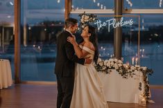 a bride and groom sharing a first dance at their wedding reception in front of the waterfront