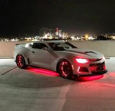 a white sports car with red lights on it's hood parked in an empty lot