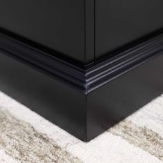 a close up view of the base of a black cabinet with white carpet on it