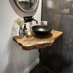 a bathroom sink sitting under a mirror next to a black bowl on top of a wooden counter