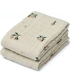 three folded blankets are stacked on top of each other, with peachs and leaves printed on them