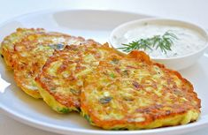 two fritters on a white plate with dipping sauce