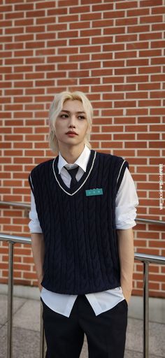 a man with blonde hair wearing a black sweater vest