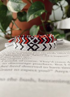 two bracelets sitting on top of an open book next to a potted plant