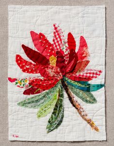 a piece of fabric with red and green flowers on it's side, sitting on top of a white cloth