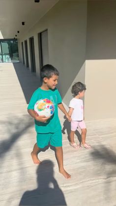 two young children are walking down the sidewalk with a frisbee in their hands