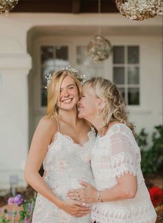 two women standing next to each other in front of a house