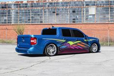 a blue pick up truck parked in front of a brick building with graffiti on it