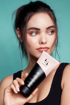 a woman holding a tube of sunscreen in front of her face