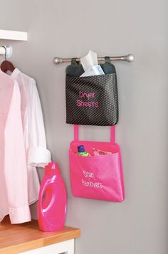 a pink purse hanging on the wall next to a white coat rack with clothes and other items