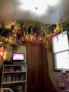 a living room decorated with plants and lights on the ceiling, along with bookshelves