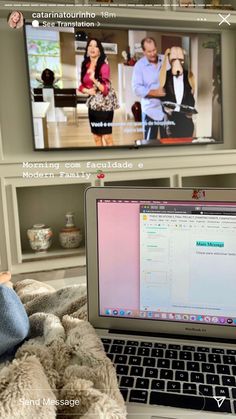 a laptop computer sitting on top of a bed in front of a flat screen tv