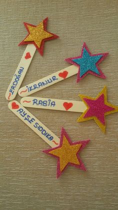 four wooden stars with names and hearts on them, arranged in the shape of magnets