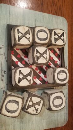 some type of dice with letters and numbers on them sitting in a wooden box next to a wood table