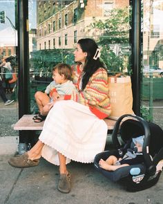 a woman sitting on a bench next to a baby in a stroller