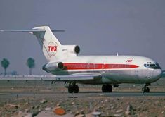 an airplane that is sitting on the ground near some rocks and gravel, with trees in the background