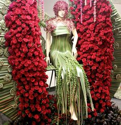 a mannequin dressed in green and red surrounded by flowers