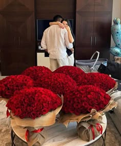 a man and woman standing next to each other in front of a large bouquet of red roses