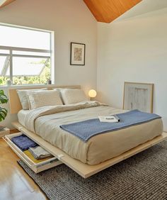 a bed sitting on top of a wooden platform in a bedroom next to a window