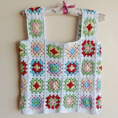 a crocheted top hanging on a wall