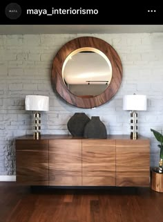 a wooden dresser sitting in front of a round mirror