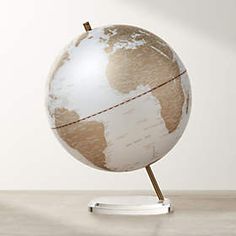 a small white and brown globe on a metal stand in front of a white wall