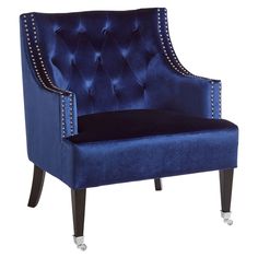 a blue velvet chair with studded legs