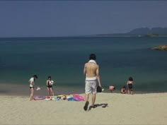 several people are on the beach and one is standing in the sand with his back to the camera