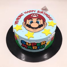 a birthday cake that is decorated with an image of mario on the top and stars around it