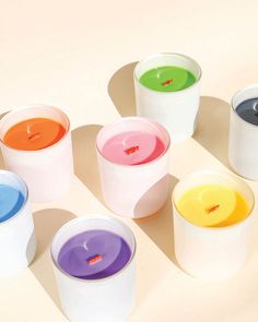 several different colored candles sitting on top of each other next to each other in white cups