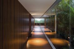 an empty hallway with wooden walls and floor to ceiling glass doors leading into another room