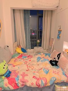 a child's bedroom with toys on the bed, and curtains in the window