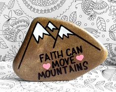 a rock with the words faith can move mountains painted on it