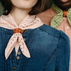 a woman wearing a denim shirt with a bow tie around her neck and another man in the background