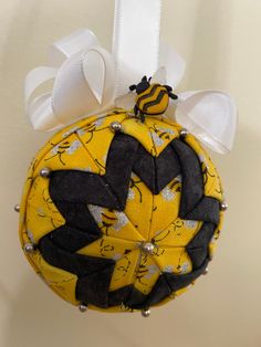 a yellow ornament with black and white designs hanging from a ribbon on a wall