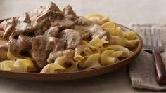 a plate full of pasta with meat and gravy on it next to a fork