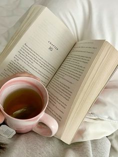 a cup of tea and an open book on a bed