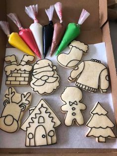 some cut out cookies sitting on top of a cardboard box next to candy sticks and markers