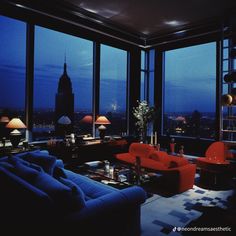 a living room filled with lots of furniture and large windows overlooking the city at night