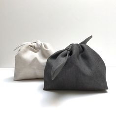 two gray and white bags sitting on top of a table next to eachother