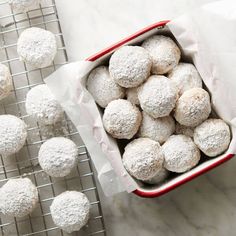 a red and white container filled with powdered sugar cookies on top of a cooling rack