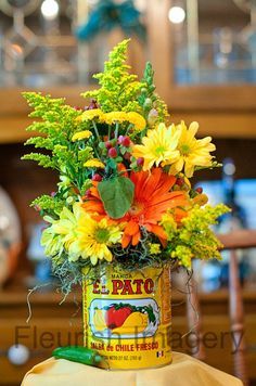 an arrangement of flowers in a can on a table