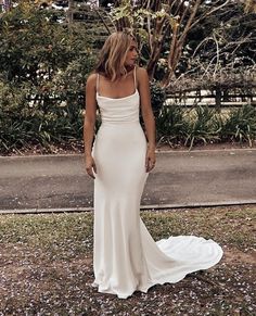 a woman wearing a white dress standing in the grass