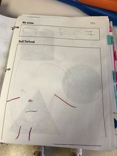 a child's hand is holding a paper with a drawing on it and some scissors