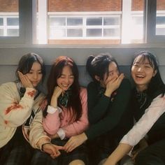 four young people sitting on a couch with their arms around each other and smiling at the camera